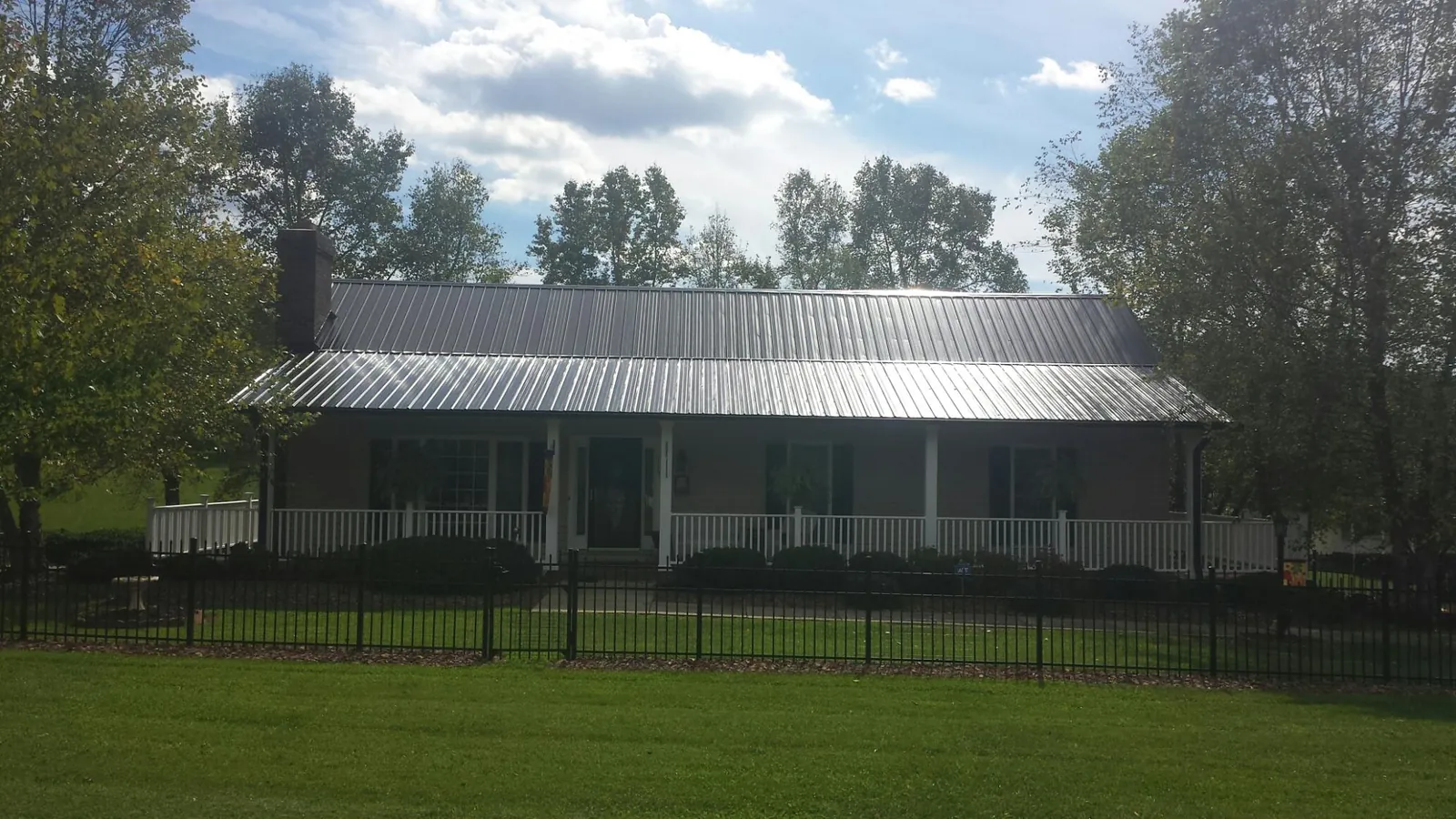 Gray metal roof on a brick ranch with a full width front porch — Gutter Guard Installation work by our crew in Yale