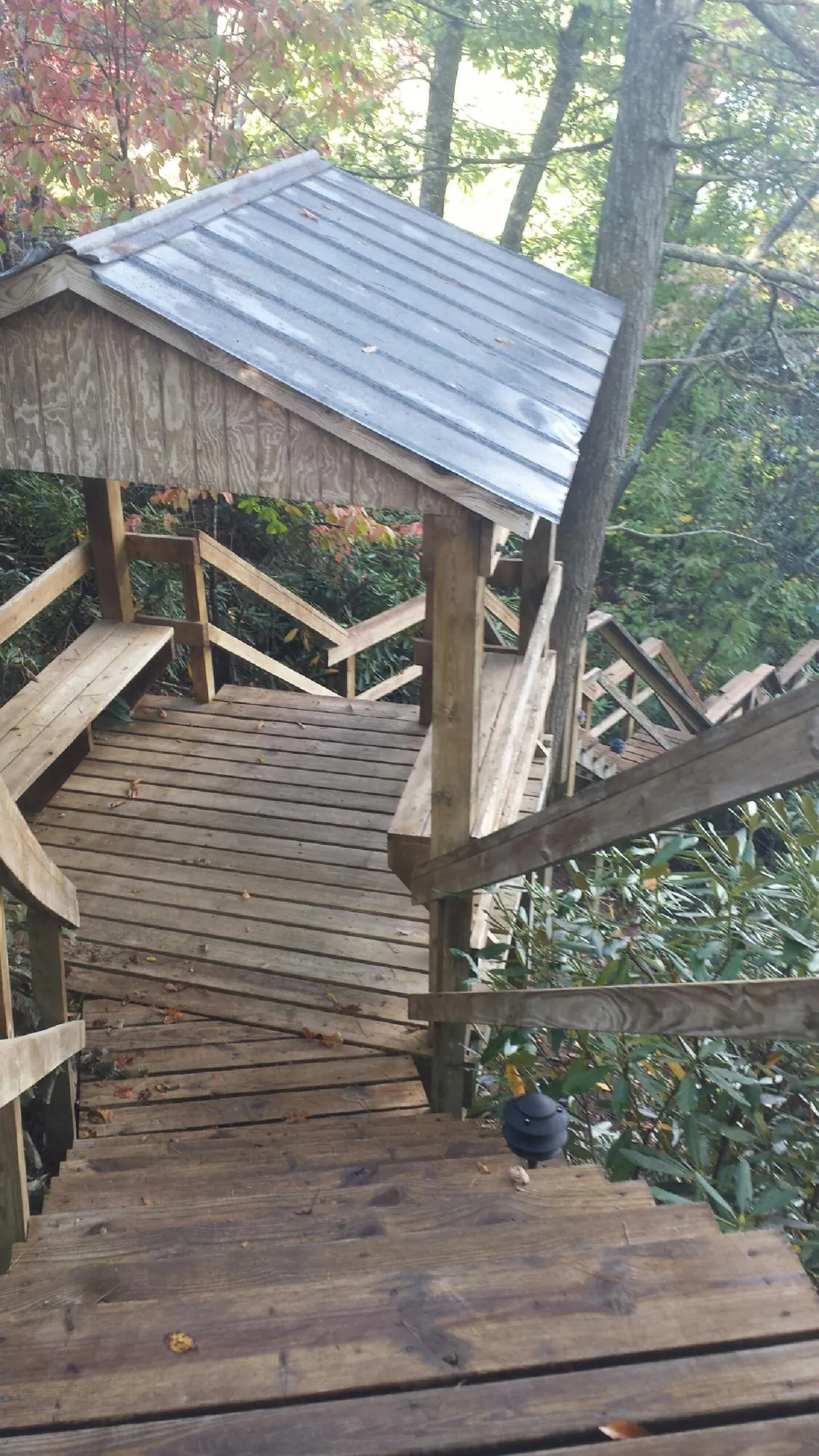 Metal roofed shelter over wooden steps on a wooded walkway — Skylight Repair & Installation work by our crew in Yale